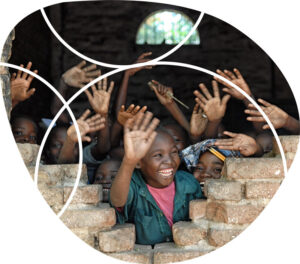 smiling children waving through an opening in a wall